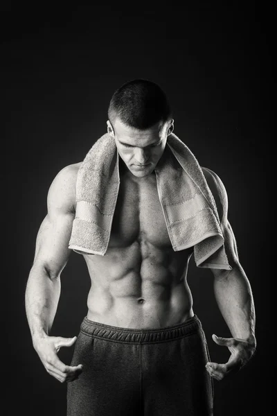 用一条毛巾在他手上一个黑暗的背景中的肌肉男 — 图库照片