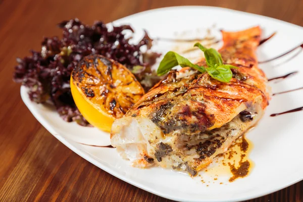 Вкусная жареная рыба, приготовленная из овощей на белой тарелке — стоковое фото