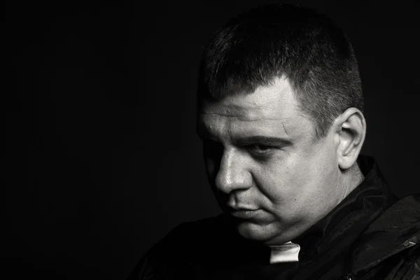 A professional stage actor in the guise of a priest against a dark background — Stock Photo, Image