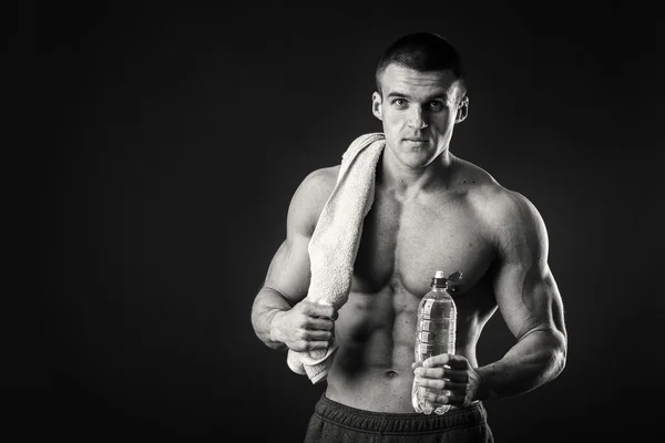 Hombre musculoso con una toalla en las manos sobre un fondo oscuro — Foto de Stock