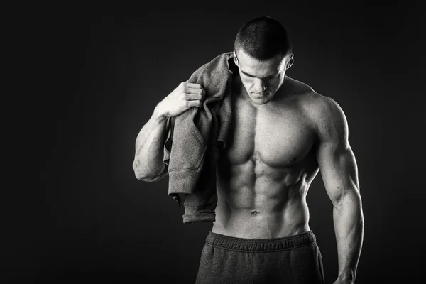 Muscular man in a sports jacket on a dark background — Stock Photo, Image