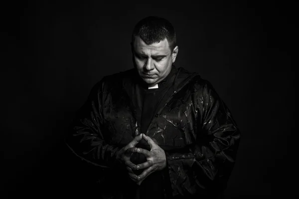Un actor teatral profesional disfrazado de sacerdote sobre un fondo oscuro — Foto de Stock