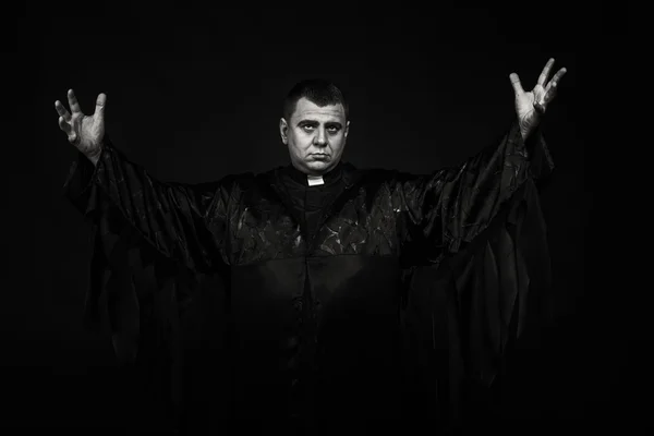 A professional stage actor in the guise of a priest against a dark background — Stock Photo, Image