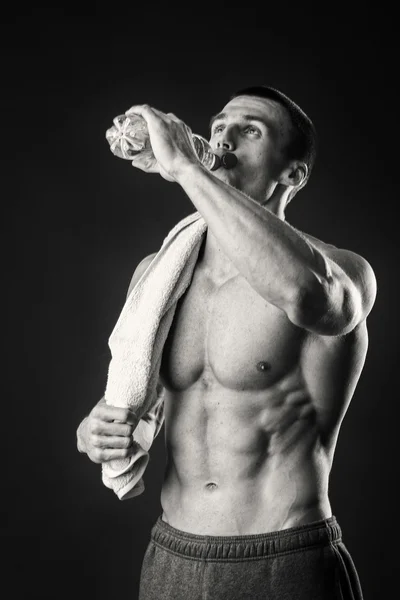 Muscular man with a towel in his hands on a dark background — Stock Photo, Image