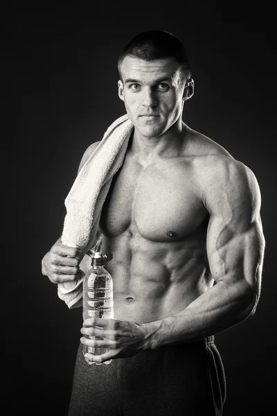 Uomo muscoloso con un asciugamano in mano su uno sfondo scuro — Foto Stock