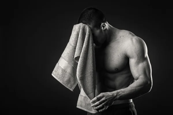 Muscular man with a towel in his hands on a dark background — Stock Photo, Image