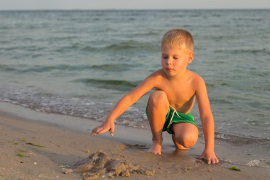 Sahilde kumda oynayan genç bir çocuk
