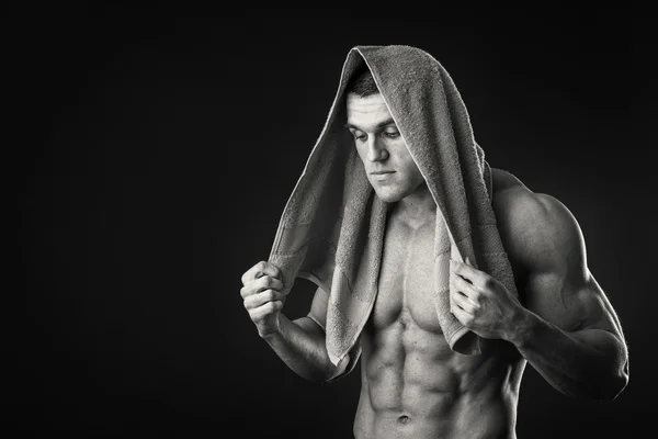 暗い背景に彼の手でタオルを持つ筋肉男 — ストック写真