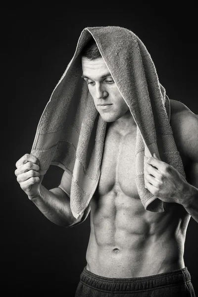 Kaslı adam ellerini karanlık bir arka plan üzerine bir havlu ile
