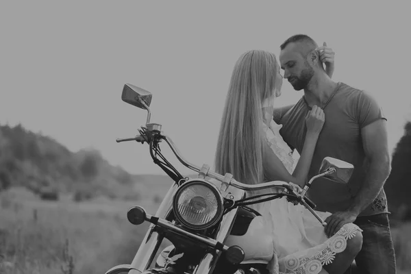 Homem musculoso com uma mulher bonita em uma motocicleta no meio de uma estrada de campo — Fotografia de Stock