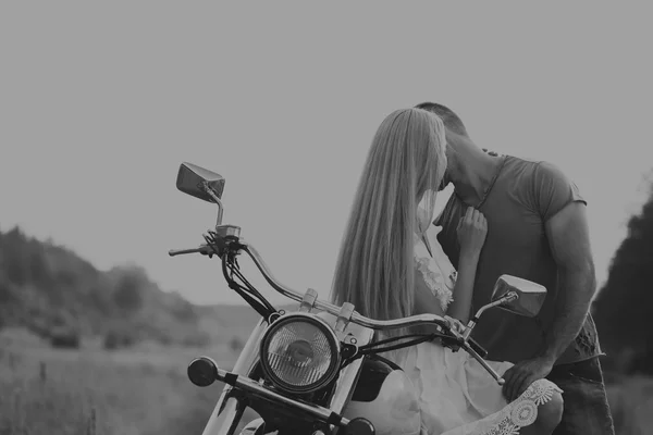 Homem musculoso com uma mulher bonita em uma motocicleta no meio de uma estrada de campo — Fotografia de Stock