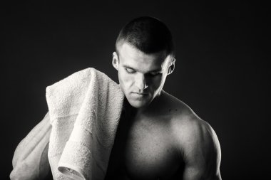 Kaslı adam ellerini karanlık bir arka plan üzerine bir havlu ile