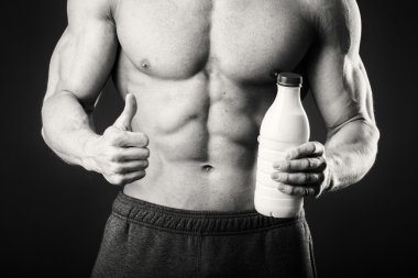 Bir şişe süt karanlık bir arka plan üzerinde vücut geliştirmeci