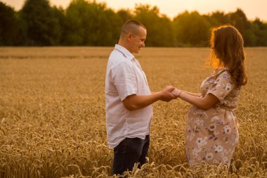 Genç bir adam ve taze kesilmiş buğday buğday tarlasında oturan bir hamile kadın