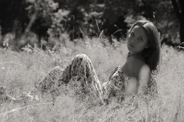 一个年轻、 有吸引力的女孩，在美丽的夏天穿衣服中间的阳光明媚的草地 — 图库照片