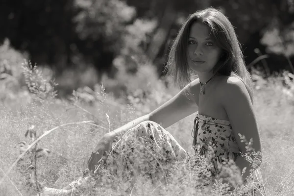 Ein junges und attraktives Mädchen im schönen Sommerkleid inmitten sonniger Wiesen — Stockfoto