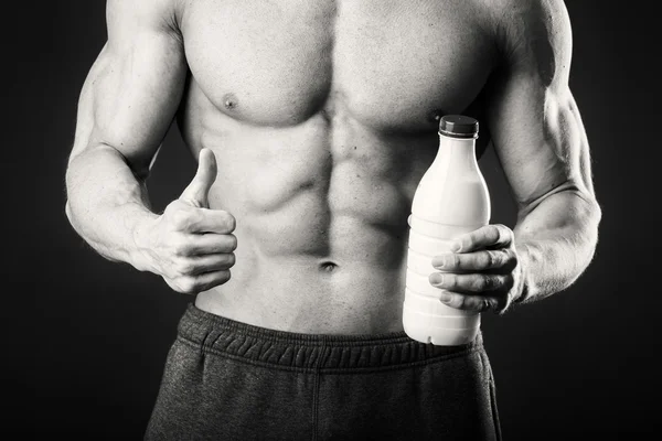 Bir şişe süt karanlık bir arka plan üzerinde vücut geliştirmeci