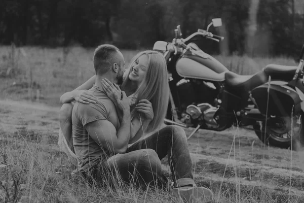Muscular man with a beautiful woman on a motorcycle middle of a field road — Stock Photo, Image