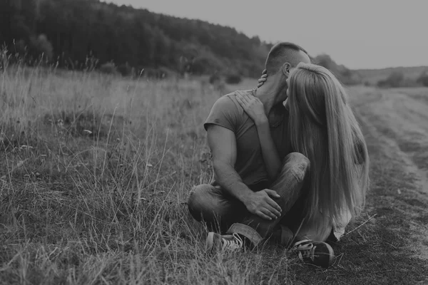 Homem musculoso com uma mulher bonita em uma motocicleta no meio de uma estrada de campo — Fotografia de Stock