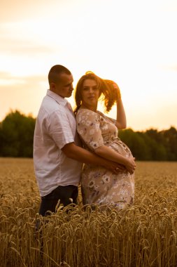 Genç bir adam ve taze kesilmiş buğday buğday tarlasında oturan bir hamile kadın