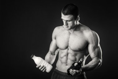 Bir şişe süt karanlık bir arka plan üzerinde vücut geliştirmeci