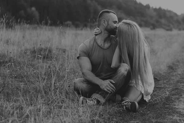 Uomo muscolare con una bella donna su una moto nel mezzo di una strada di campo — Foto Stock