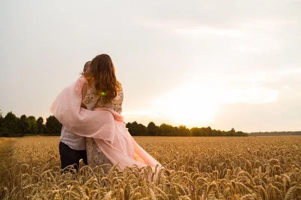 Genç bir adam ve taze kesilmiş buğday buğday tarlasında oturan bir hamile kadın