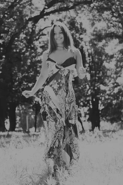 A young and attractive girl in beautiful summer dress middle of sunny meadows — Stock Photo, Image