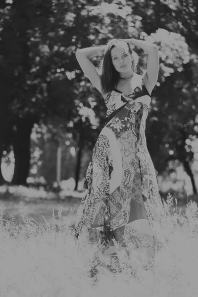 A young and attractive girl in beautiful summer dress middle of sunny meadows — Stock Photo, Image