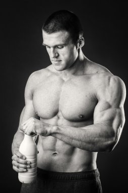 Bir şişe süt karanlık bir arka plan üzerinde vücut geliştirmeci