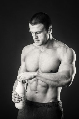 Bir şişe süt karanlık bir arka plan üzerinde vücut geliştirmeci