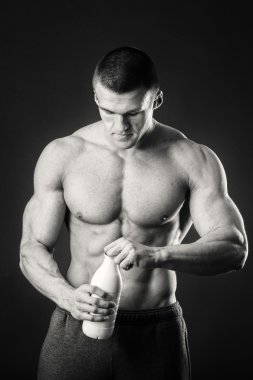 Bir şişe süt karanlık bir arka plan üzerinde vücut geliştirmeci