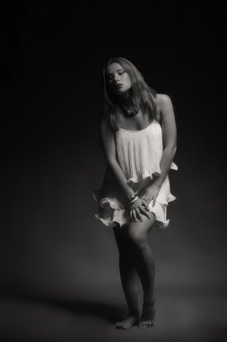 Karanlık bir arka plan üzerinde beyaz elbiseli güzel esmer