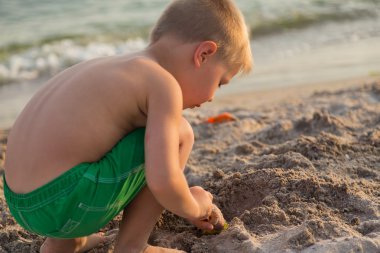 Sahilde kumda oynayan genç bir çocuk