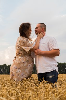 Genç bir adam ve taze kesilmiş buğday buğday tarlasında oturan bir hamile kadın