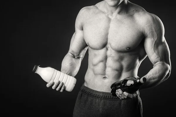 Bodybuilder met een fles melk op een donkere achtergrond — Stockfoto