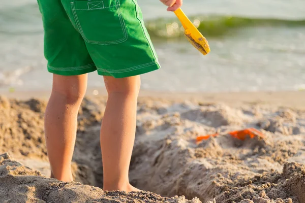 Młody chłopak bawiące się w piasku na plaży — Zdjęcie stockowe