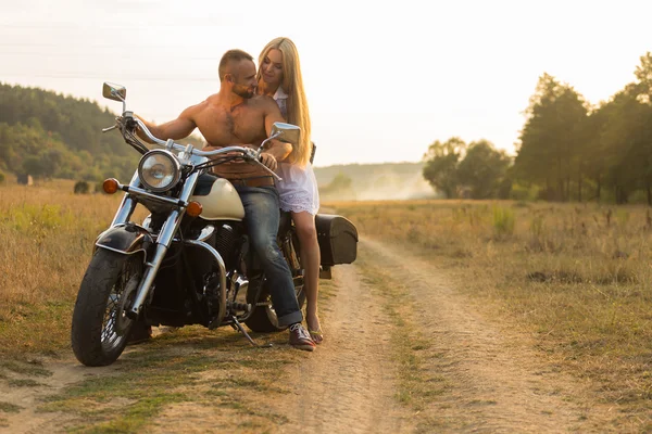 Muskularny mężczyzna z piękną kobietą na środku motocykl polną drogę — Zdjęcie stockowe