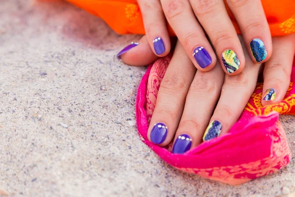 Belle mani di donne con manicure lucente su un mare di sabbia — Foto Stock