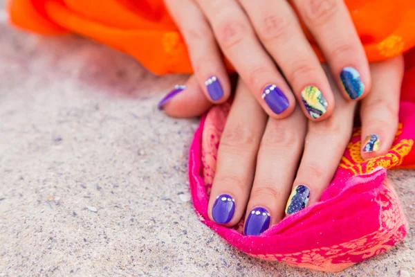 Beautiful women's hands with bright manicure on a sea of sand