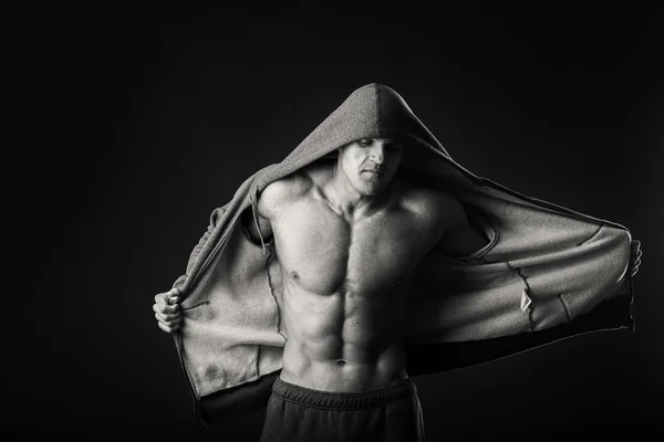 Muscular man in a sports jacket on a dark background — Stock Photo, Image