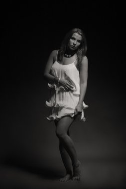 Karanlık bir arka plan üzerinde beyaz elbiseli güzel esmer