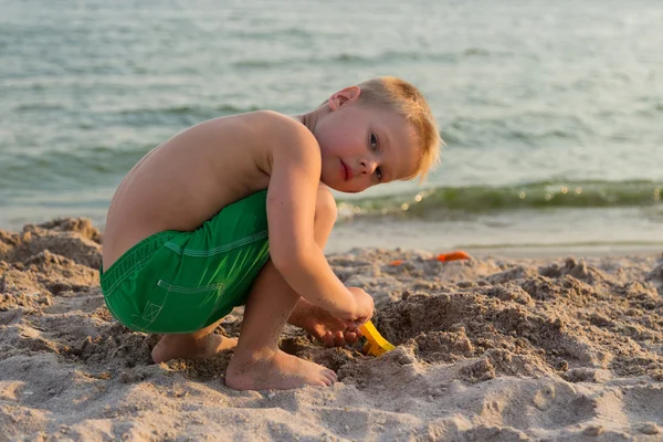 Um menino brincando na areia na praia — Fotografia de Stock
