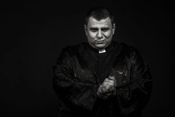 A professional stage actor in the guise of a priest against a dark background — Stock Photo, Image