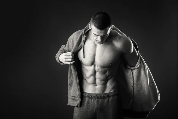 Muscular man in a sports jacket on a dark background — Stock Photo, Image