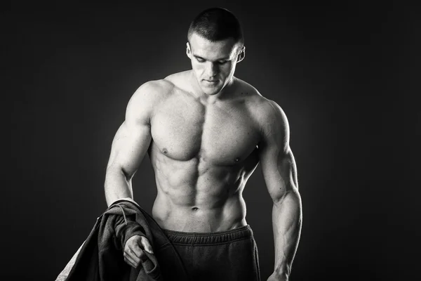Homem muscular em uma jaqueta de esportes em um fundo escuro — Fotografia de Stock