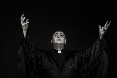 Karanlık bir arka plan karşı bir rahip kılığında bir profesyonel tiyatro oyuncusu