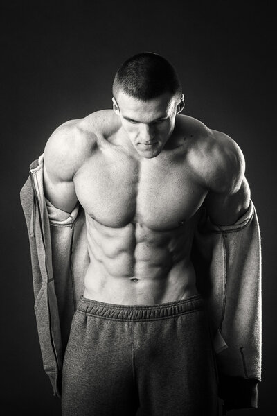Muscular man in a sports jacket on a dark background