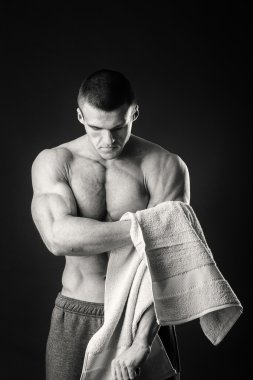 Kaslı adam ellerini karanlık bir arka plan üzerine bir havlu ile