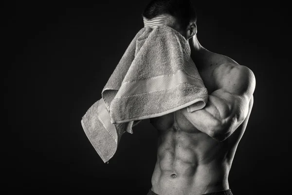 Muscular man with a towel in his hands on a dark background — Stock Photo, Image